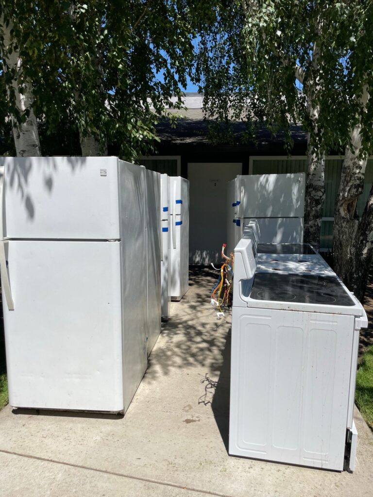 Old refrigerators and electric stoves lined up for appliance removal and recycling