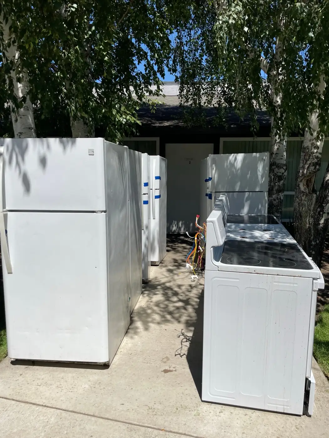Old refrigerators and electric stoves lined up for appliance removal and recycling