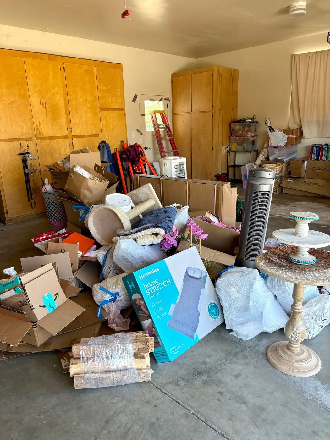 Garage cleanout before: boxes, bags, furniture and household junk piled in the middle of the garage