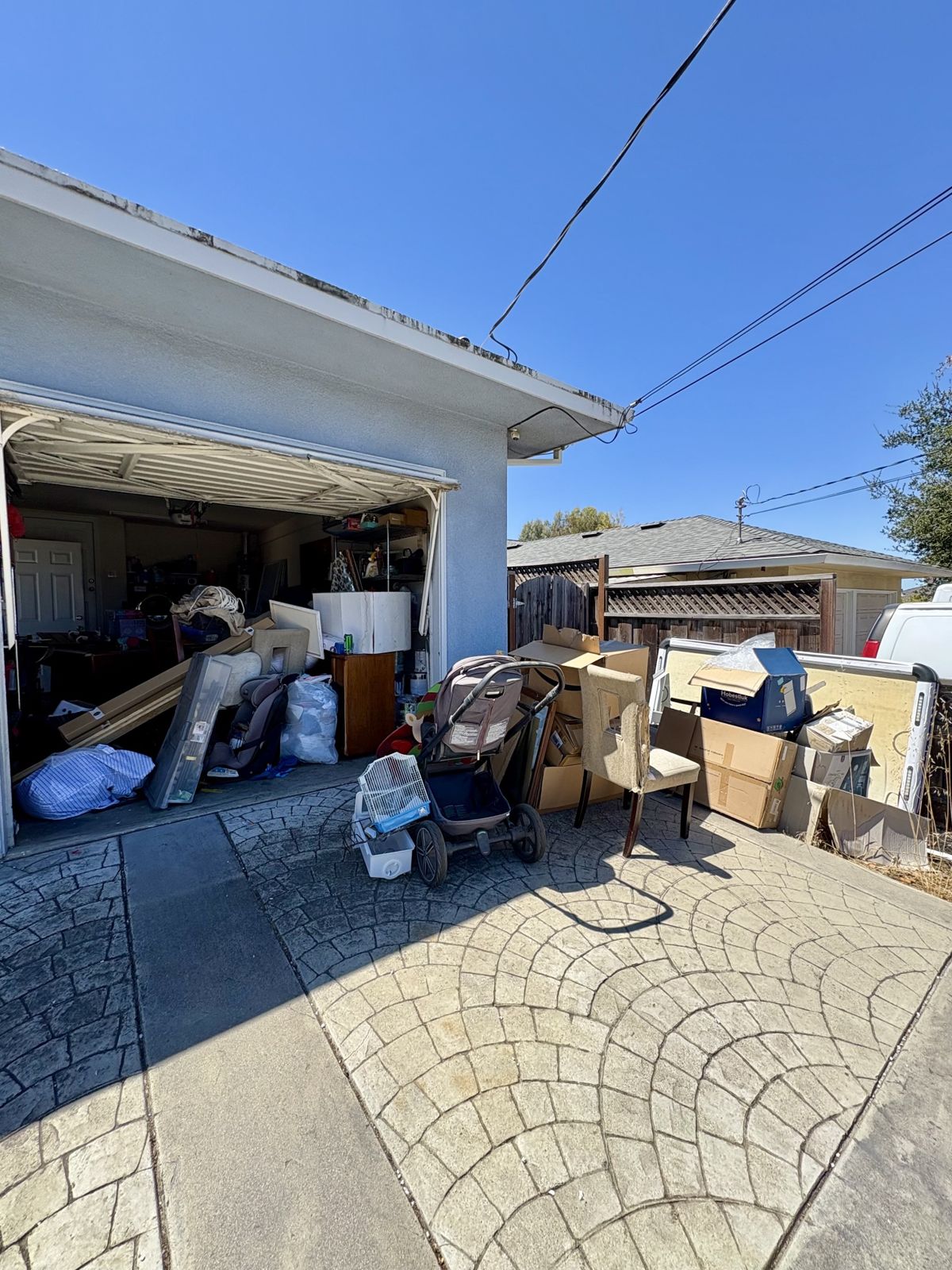 Garage and driveway piled with boxes, furniture, and household items before move-out junk removal