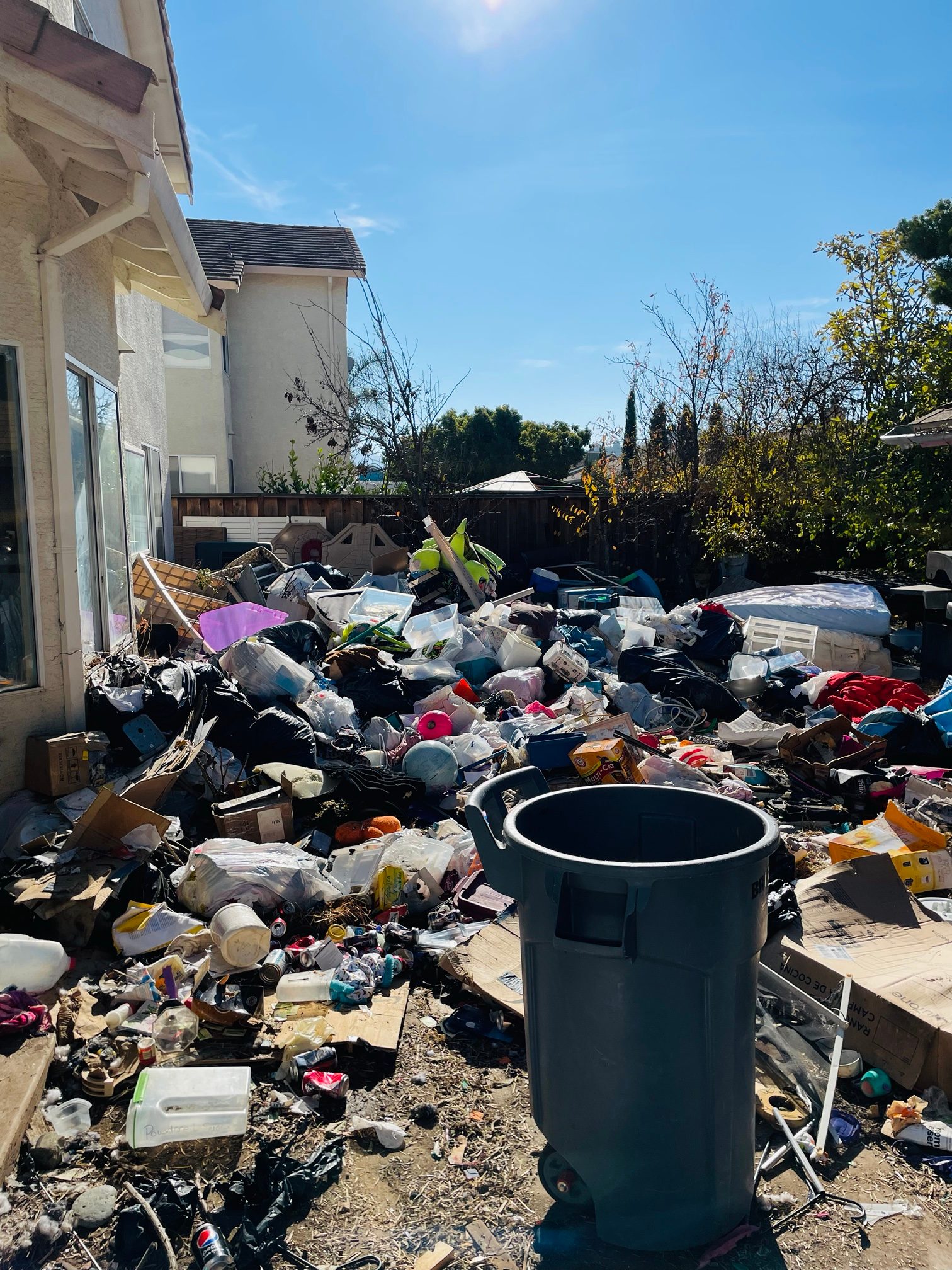Backyard buried in trash and household items before a hoarder cleanout