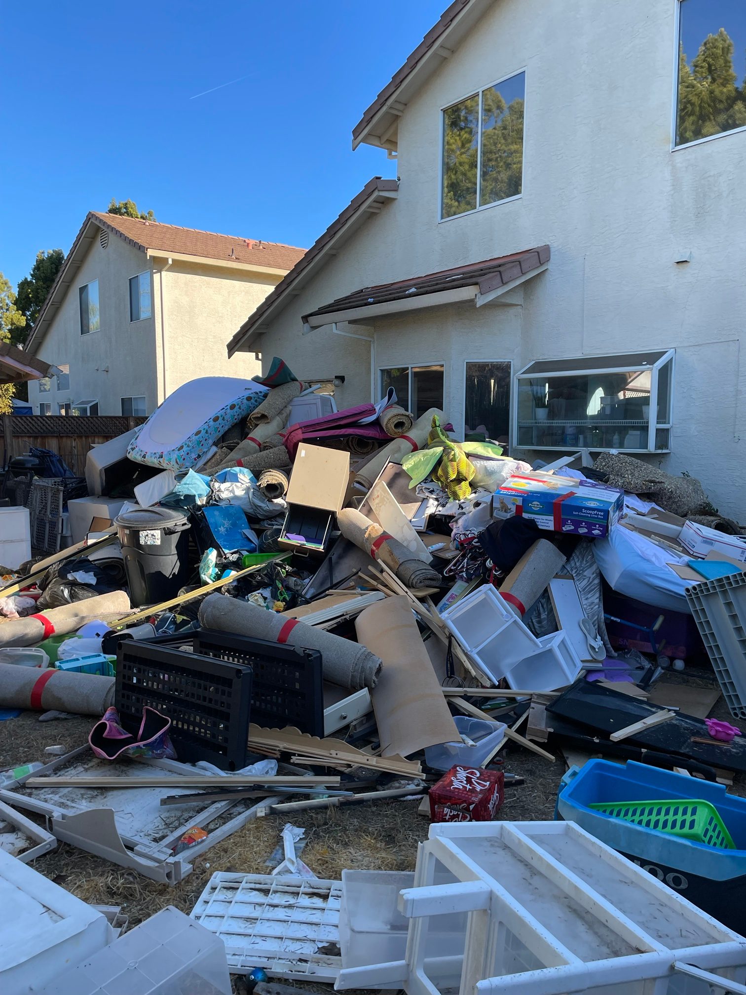 Large pile of carpet, furniture and household items behind a home before a hoarder cleanout