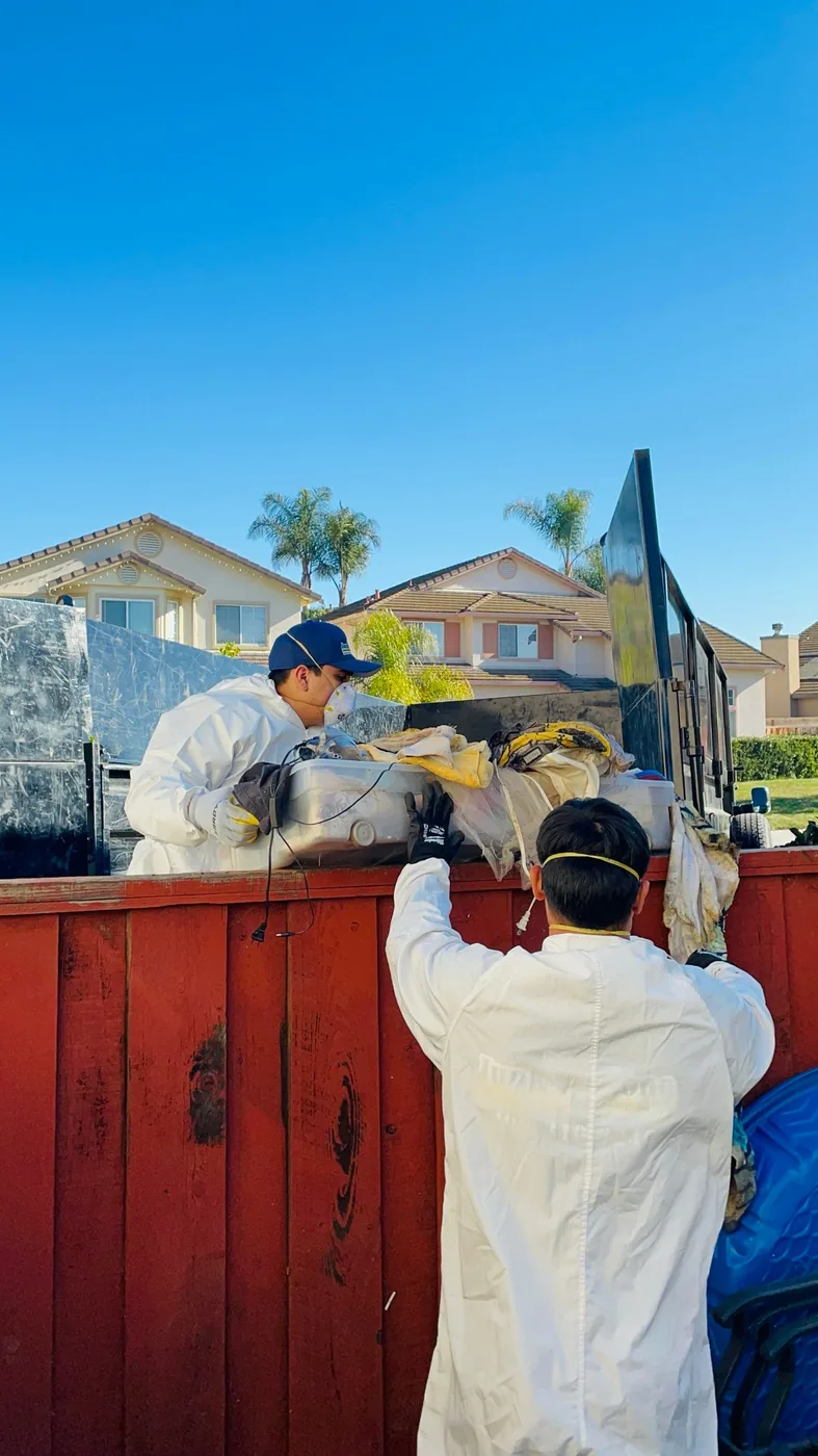Junk Gone crew in protective suits and masks loading the trailer during a hoarder cleanout