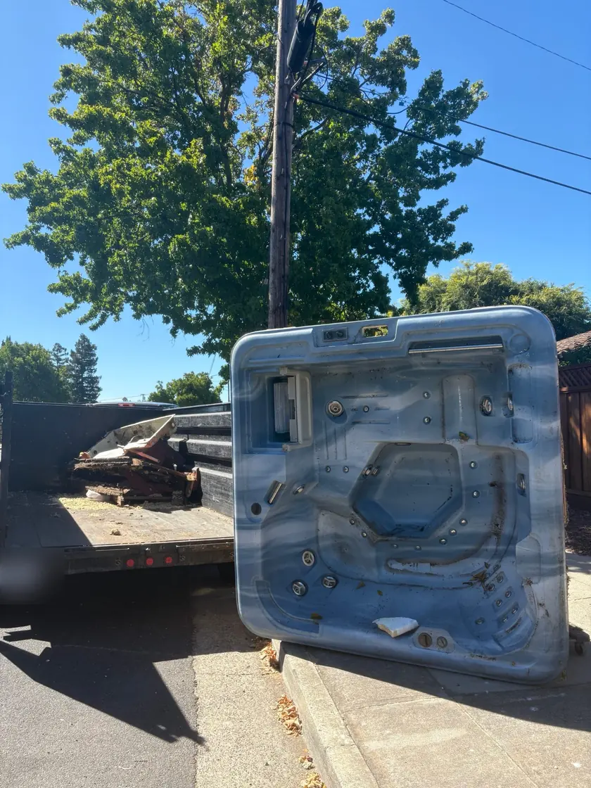 Old hot tub pulled out to the curb next to the Junk Gone trailer