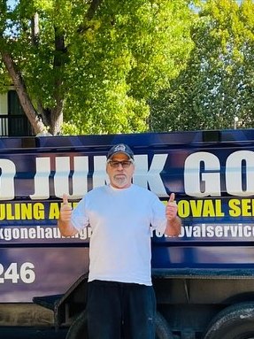 Happy customer with arms out in front of the Junk Gone trailer