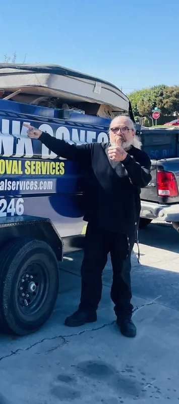 Happy customer pointing at the full Junk Gone trailer