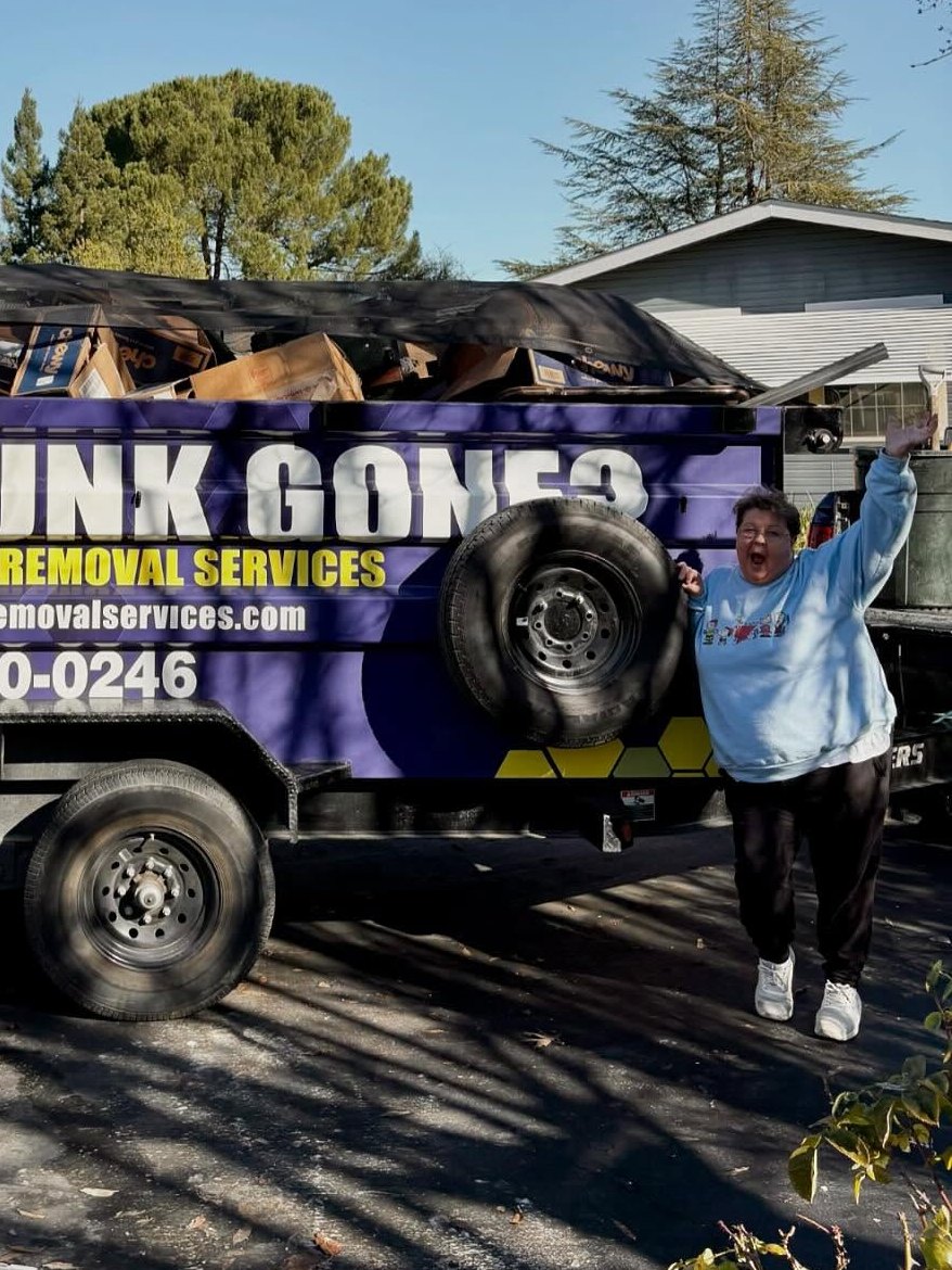 Customer waving next to a loaded Junk Gone trailer