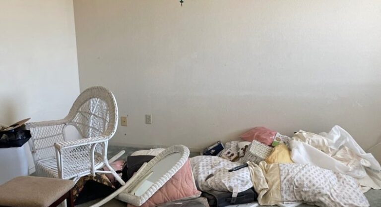 Room with piled bedding and furniture before cleanout