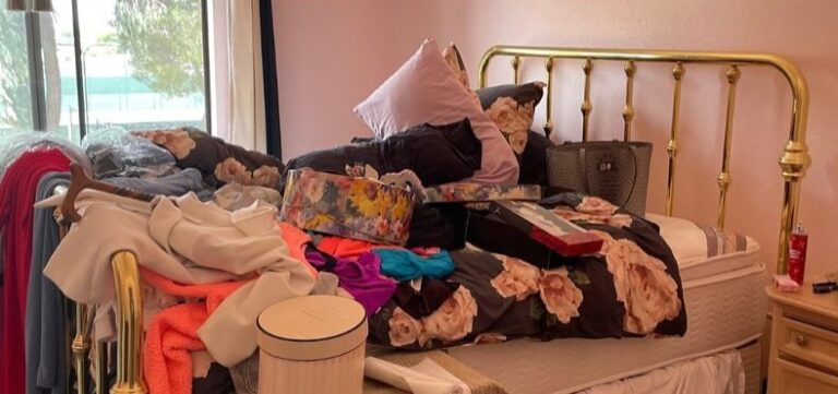 Bedroom piled with clothes and boxes before cleanout