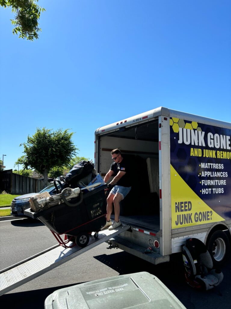 Junk Gone crew wheeling a full cart of junk up the ramp into the box truck