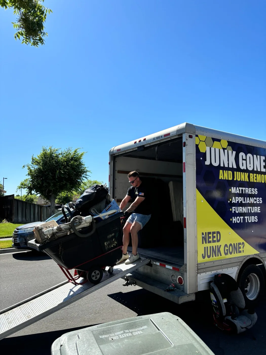Junk Gone crew wheeling a full cart of junk up the ramp into the box truck