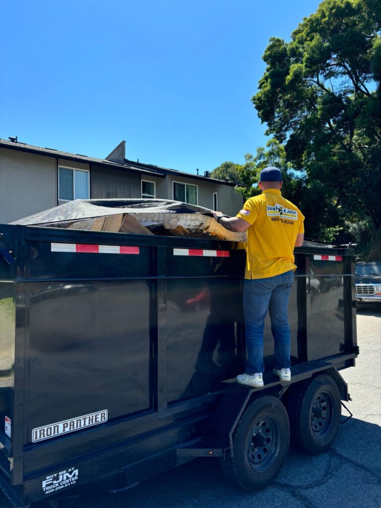 Junk Gone crew member tarping a full dump trailer load