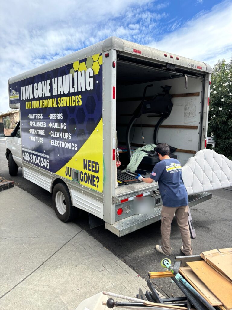 Junk Gone crew loading a headboard and treadmill into the branded box truck