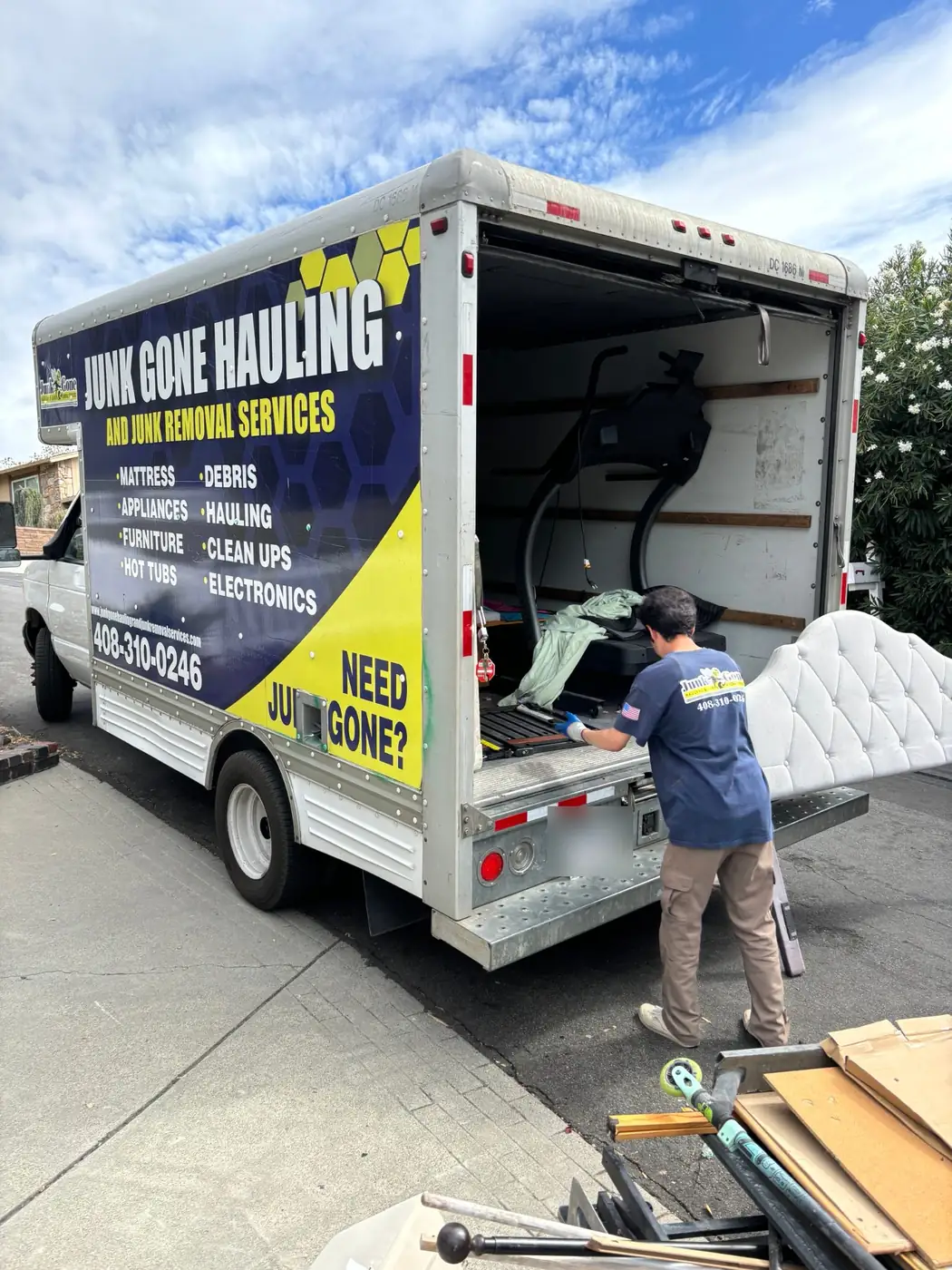 Junk Gone crew loading a headboard and treadmill into the branded box truck