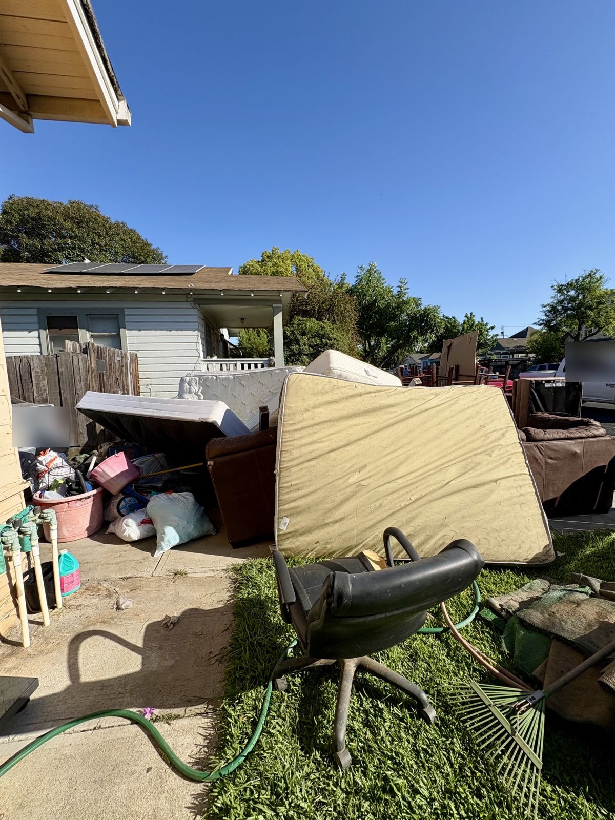 Front yard piled with mattresses and couches before junk removal