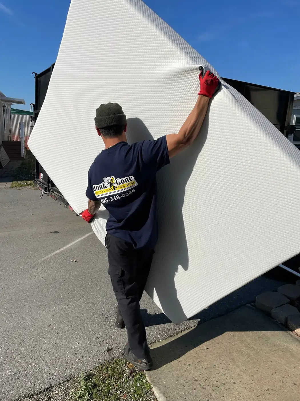 Junk Gone crew member carrying a mattress to the trailer for recycling